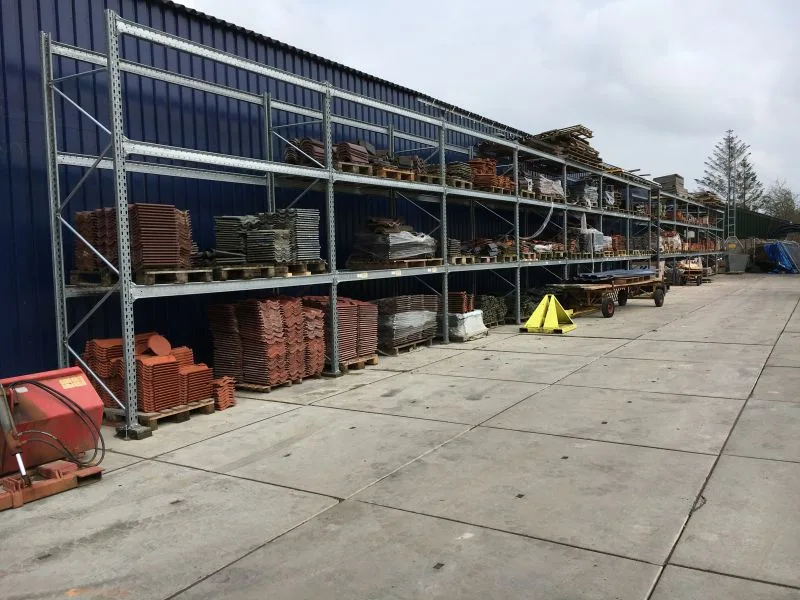 palletstelling verzinkt. vol met bouwmaterialen zoals dakpannen voor een blauwe loods