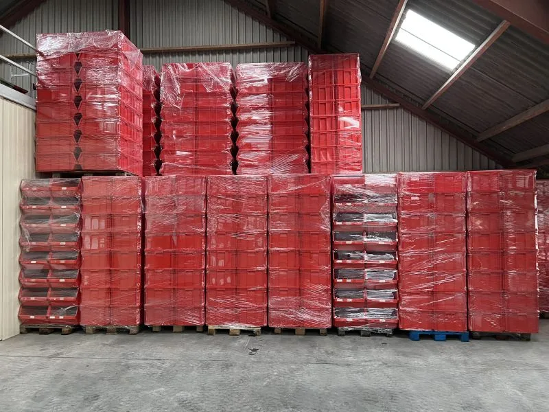 opgestapelde pallets vol met rode grijpbakken