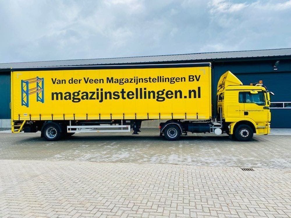 gele vrachtwagen met ligger met daarop de naam en logo van magazijnstellingen.nl